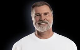 Portrait of an older man aged 55+ with gray hair and beard wearing a white t-shirt